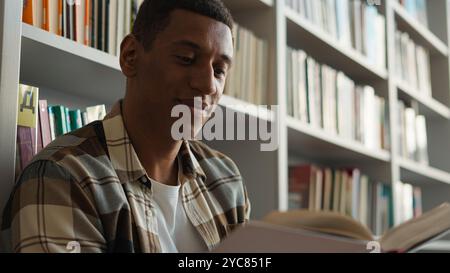 African American man guy library reading book textbook high school exam preparation university college academy study learning student reader bookworm Stock Photo