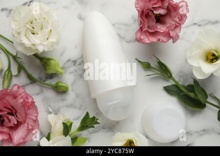 Roll-on deodorant and beautiful eustoma flowers on white marble table, flat lay Stock Photo