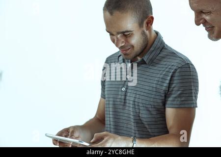 Two male colleagues are engrossed in a digital tablet project, their focused expressions reflecting their dedication to achieving a successful outcome Stock Photo