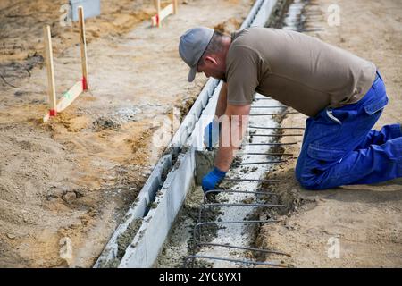 Close up of a bricklayer worker making cement mortar on a wall block  Stock Photo