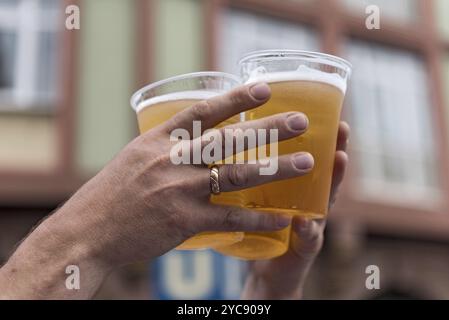 Two hands and three full plastic cups with beer Stock Photo