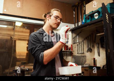 Man, carpenter and checking with tools for size, precision or accuracy in woodwork at manufacture. Young, male person or creative artisan with Stock Photo