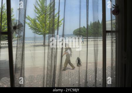 11.08.2012, Wonsan, North Korea, Asia, A view through the window of a restaurant shows an everyday street scene in the coastal city of Wonsan, Asia Stock Photo