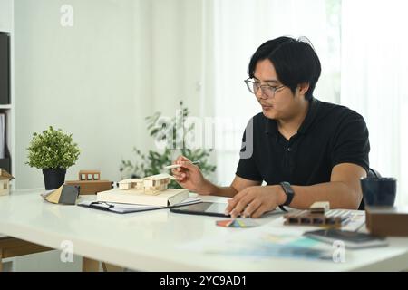 Architect working on a miniature house model in modern office office Stock Photo