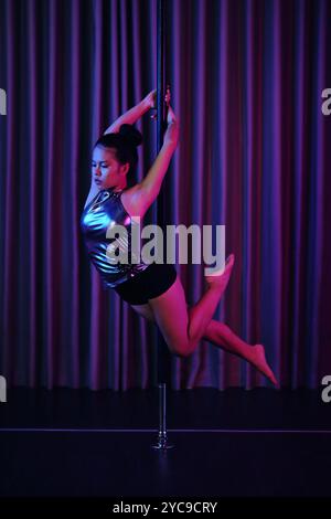 Performing Pole Dance with Vibrant Stage Lighting Stock Photo