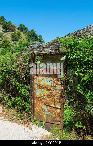 An old metal garden gate in a traditional stone wall in Gjirokaster historic old town in south Albania. Gjirokaster is famous for Ottoman architecture Stock Photo
