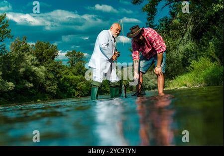 Father and adult son fishing lakeside. Having a good time. Fisher fishing equipment. Giving your hobby. Master baiter. I am happiest man. Angler Stock Photo