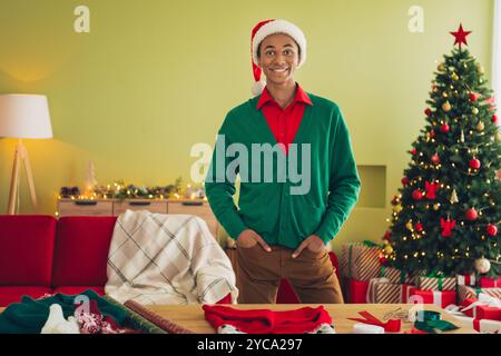 Photo of cheerful positive guy dressed green pullover ready wrapping x-mas gifts indoors house apartment room Stock Photo
