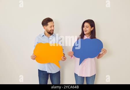 Holding paper speech bubbles couple playful banter faces smiling and joy. Speech bubbles capture essence of light hearted exchanges creating moments Stock Photo