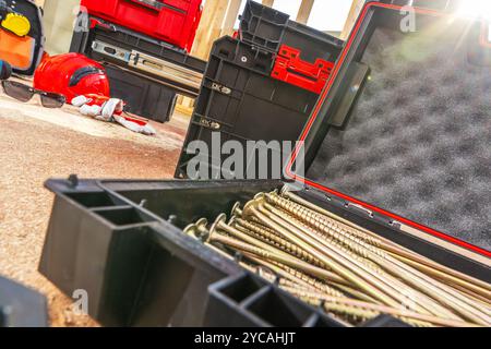A variety of tools and equipment are arranged in a workshop, highlighting metallic screws in a toolbox and other gear. The atmosphere suggests a busy Stock Photo