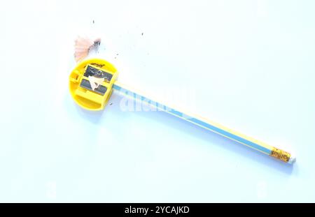 pencil shaving  in yellow plastic sharpener arranging on white background Stock Photo