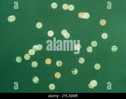 Festive flat-lay arrangement featuring green glittery baubles scattered across green background. Top view. Copy space. Minimal Christmas or New year b Stock Photo