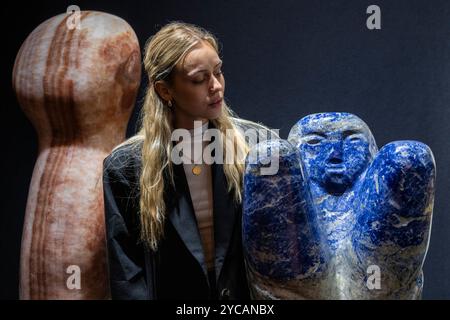 London, UK.  22 October 2024. A staff member with (R) 'Observer', 2024, by Paul Vanstone, Bolivian blue marble, at a preview of the LAPADA fair by the Association of Art & Antiques Dealers.  Specialist dealers are presenting a diverse range of art, design and antiques with authenticity assured thanks to a 70-member specialist committee pre-vetting everything on sale.  The fair runs 22 to 27 October in Berkeley Square.  Credit: Stephen Chung / Alamy Live News Stock Photo