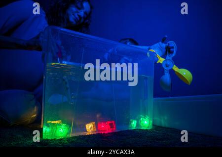 Child and therapist in sensory stimulating room, black snoezelen. Autistic child playing with therapist during occupational therapy session. Stock Photo