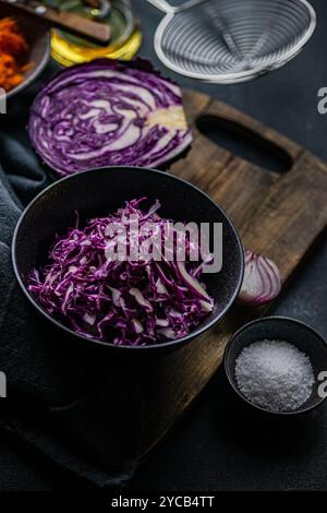 A selection of fresh salad ingredients including chopped red cabbage, sliced red onion, shredded carrot, olive oil, and sea salt, arranged on a dark w Stock Photo