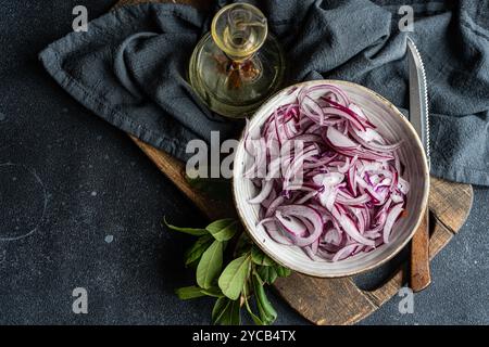 Sliced red onions mixed with black pepper, bay leaves, and sea salt are prepared for fermentation Bottle of spicy oil adds intense flavor, all set on Stock Photo