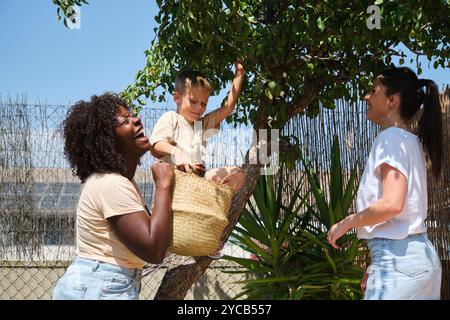A cheerful multiracial family spends quality time outdoors on a sunny day. An African American woman laughs joyfully while looking at her Caucasian pa Stock Photo