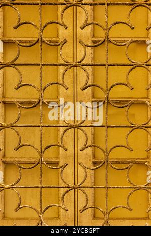 Close-Up of Rustic Yellow Grate Against Weathered Window Stock Photo