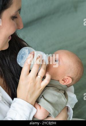 Mother feeds newborn baby formula milk from bottle. Close up of Caucasian baby. Infant nutrition. Problems with breastfeeding. Motherhood. Concept rea Stock Photo