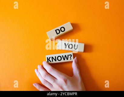 Do you know symbol. Concept word Do you know on wooden cubes. Businessman hand. Beautiful orange background. Business and Do you know concept. Copy sp Stock Photo