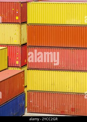 Yellow, orange and red shipping cargo containers stacked in several layers at the port terminal, stack of containers in a harbor container terminal Stock Photo