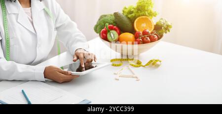Dietologist black woman using digital tablet at workplace Stock Photo