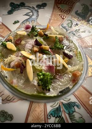 Exquisite Japanese sashimi dish artfully arranged with fresh fish slices, slivered almonds, microgreens, and edible flowers on an ornate Japanese dish Stock Photo