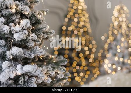 snowy fir tree close-up with garland and blurred lights in the background. New Year and Christmas celebration concept Stock Photo