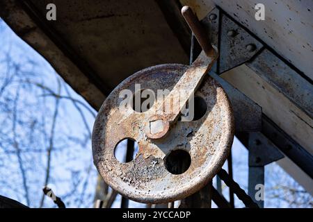 old, rusty hand crank attached to the wooden beam Stock Photo