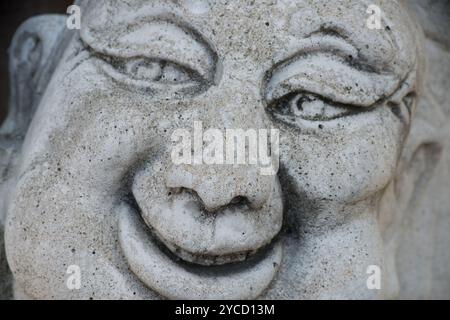 A close-up of a smiling, happy  Buddha concrete statue. Stock Photo