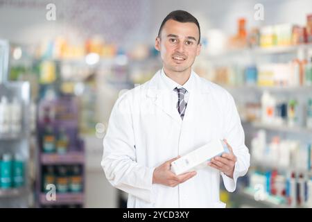Young male pharmacist demonstrating preparation in box Stock Photo