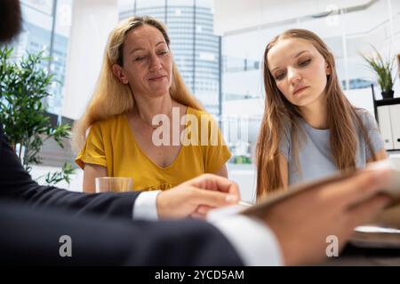 Portfolio Manager in office analyzing economic reports, developing investment objectives and discussing with people wanting to invest. Financial advisor helping family looking to grow their wealth Stock Photo