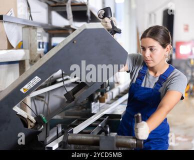 Female machinist operating industrial profile cutting machine Stock Photo