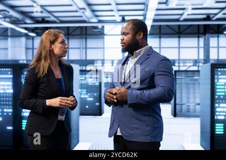 Team of engineers doing disaster recovery planning and security protocol enforcement in data center. Teamworking colleagues in server room reducing downtime, ensuring business continuity Stock Photo