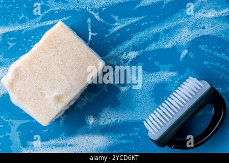 foam sponge for washing dishes on blue ceramic table with copy space. Cleaning sponge and brush for cleaning on wet surface. Stock Photo