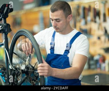 Young male worker oiling bicycle wheel Stock Photo