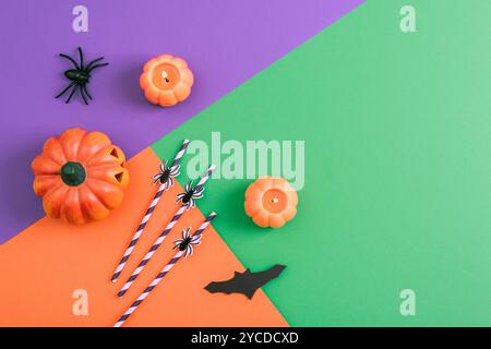 Stylish Halloween background with pumpkins, bats, and drinking straws with spiders on an orange, purple and green backdrop. Seasonal advertisement and Stock Photo