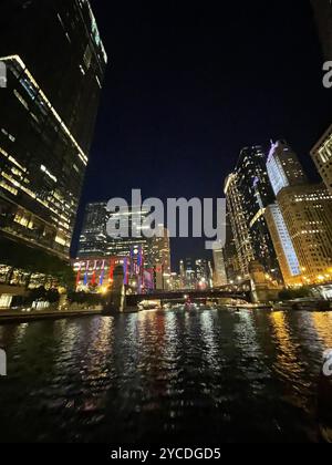 Chicago River winds through illuminated skyscrapers, their lights dancing on dark waters as bridges connect the urban canyons in a nocturnal ballet. Stock Photo