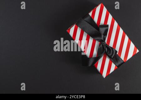 Red striped box with bow on black background for black friday new year Stock Photo