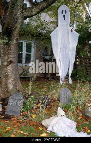 Halloween decorations, white ghosts and tombstones with RIP written on them, in front of  a house Stock Photo