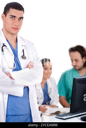 Serious young doctor looking at the camera, two others making notes in the background Stock Photo
