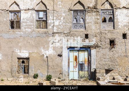 Old, weathered shutters and front door in the deserted neighbourhood of Mirbat, Dhofar Province, Arabian Peninsula, Sultanate of Oman Stock Photo