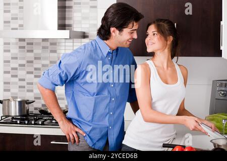 Smiling young couple enjoying their love in kitchen Stock Photo