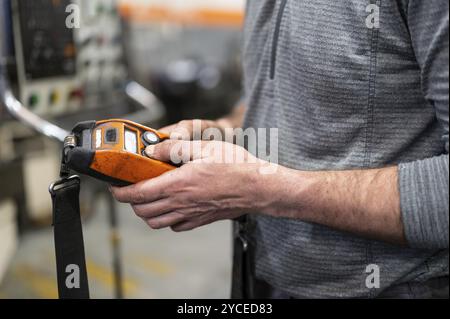 Factory worker. Technician controlling a heavy crane in factory, close up at his hands holding a crane controller. Stock Photo