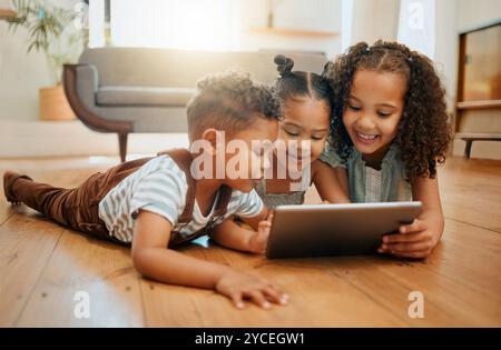 Siblings, children and tablet on floor in home for playing games, watching online cartoons and bonding together. People, kids and digital tech in Stock Photo