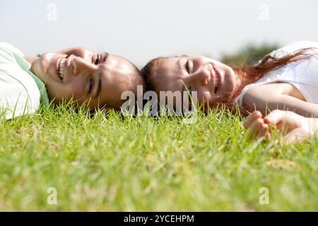 A young couple laying down and relaxing on a  grass lawn Stock Photo