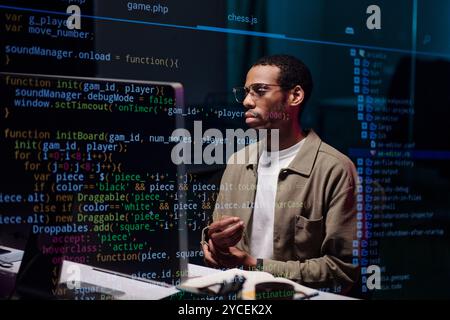 African American Coder Analyzing Complex Code on Screen Stock Photo