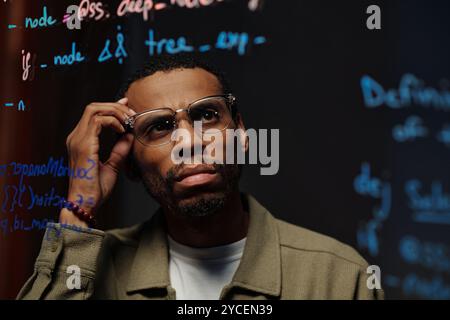 Thoughtful Man Analyzing Data on Transparent Board Stock Photo