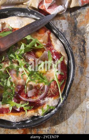 Pizza base with whole wheat flour with arugula and onion Stock Photo