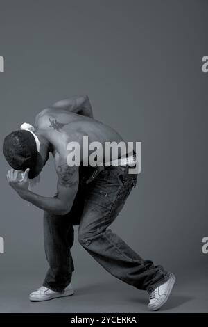 Young teenager performing dance movements on grey background Stock Photo